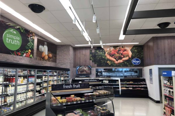 Grocery store interior with refrigerated dairy section, fresh fruit display, and signage for Simple Truth and Kroger brands.