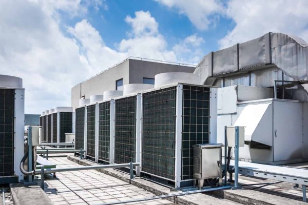 Rooftop view of large industrial HVAC units and ventilation systems under a partly cloudy sky.